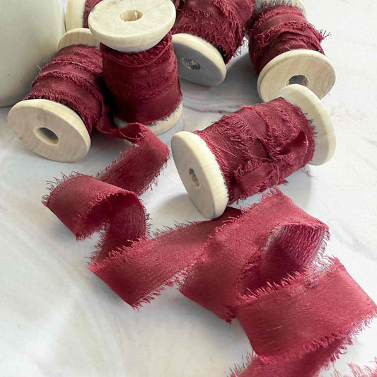 Red ribbon on wooden spools on a white surface