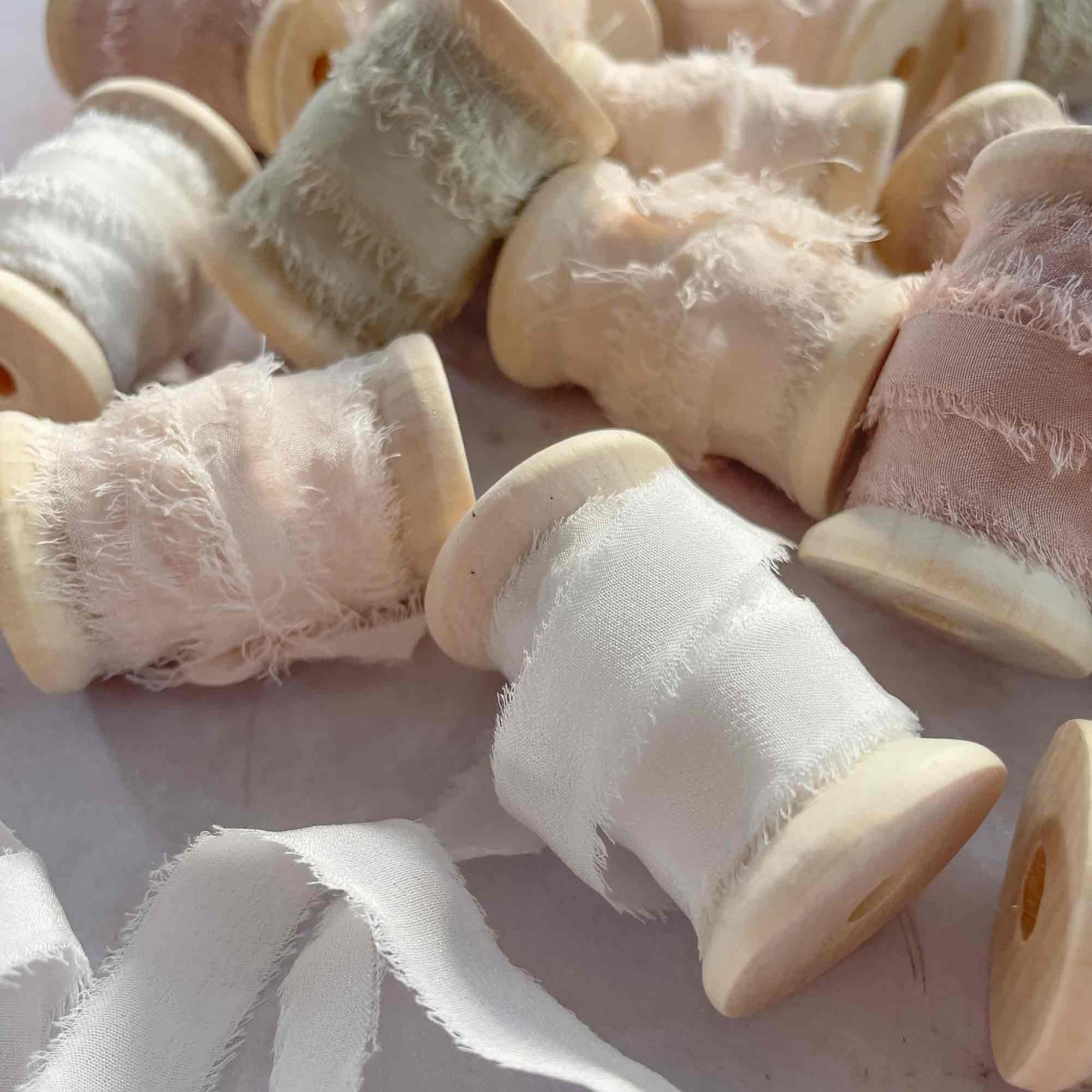 Narrow silk ribbon on a wooden reel. Available in various colours. By The Natural Paper Company
