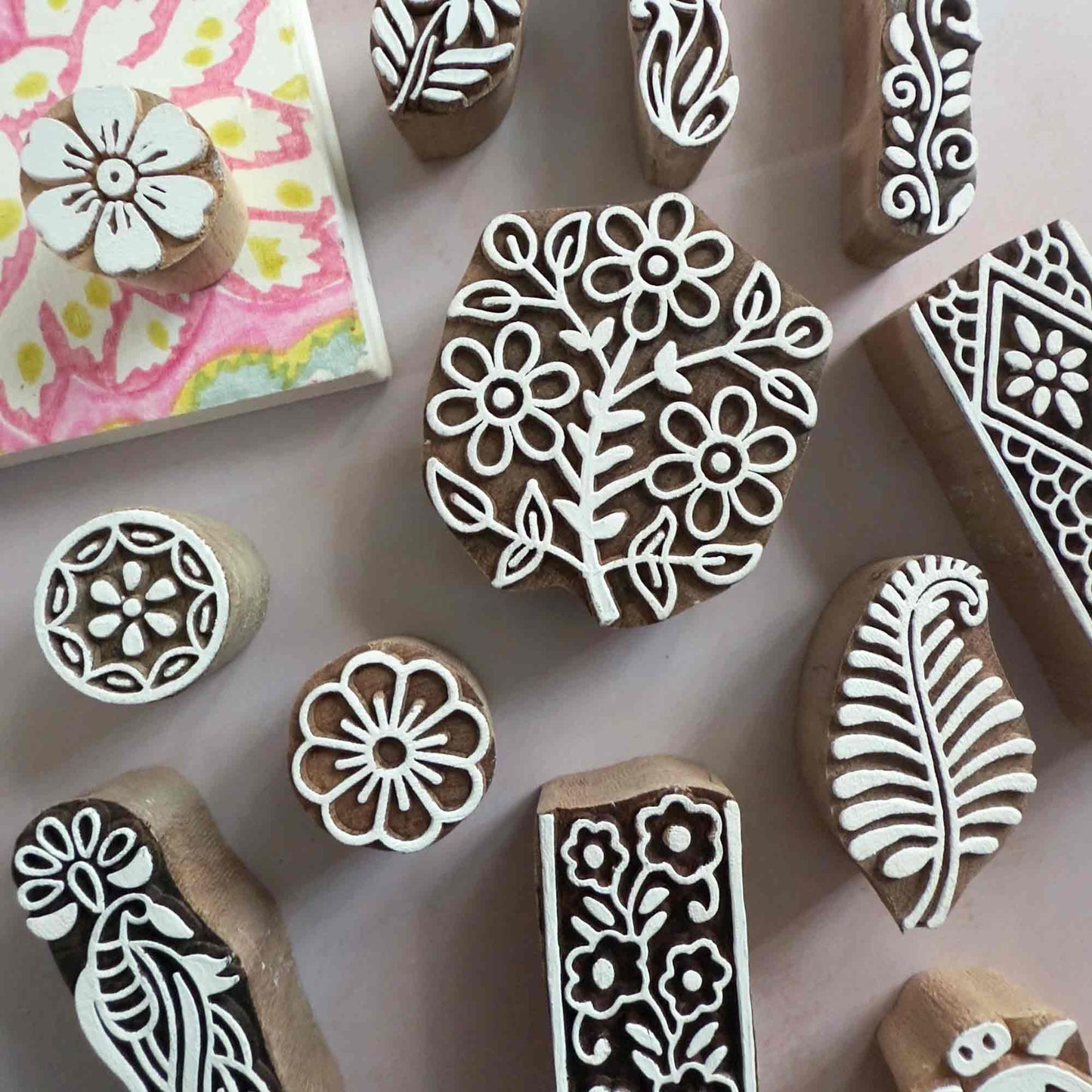 Collection of wooden stamps with floral designs on a pink background