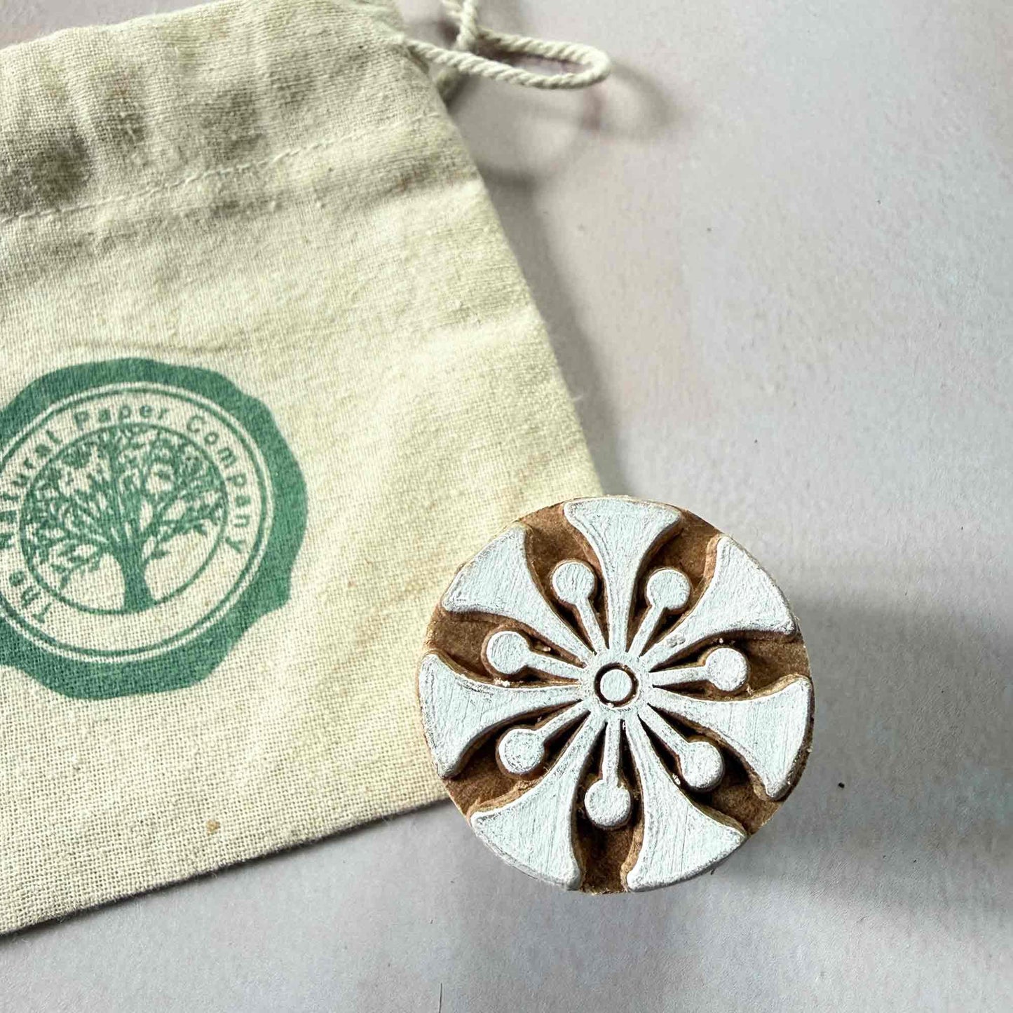 Wooden stamp with floral design next to a Branded gift bag from The Natural Paper Company