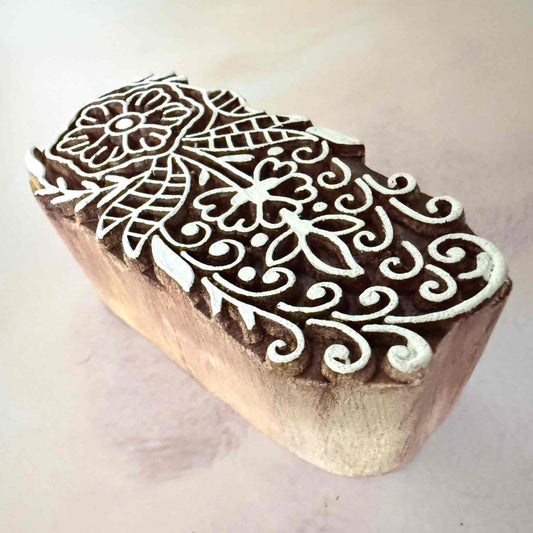 Wooden stamp block with intricate white design on a light background