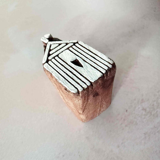Wooden stamp with a birdhouse design on a light background