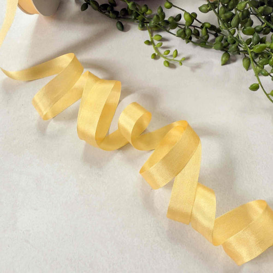 Yellow ribbon on a white surface with green leaves in the background