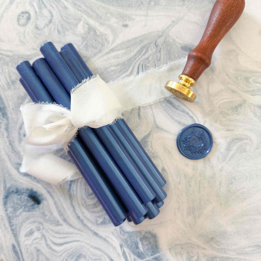 Set of blue wax sticks with a wooden handle and gold accents on a marble surface