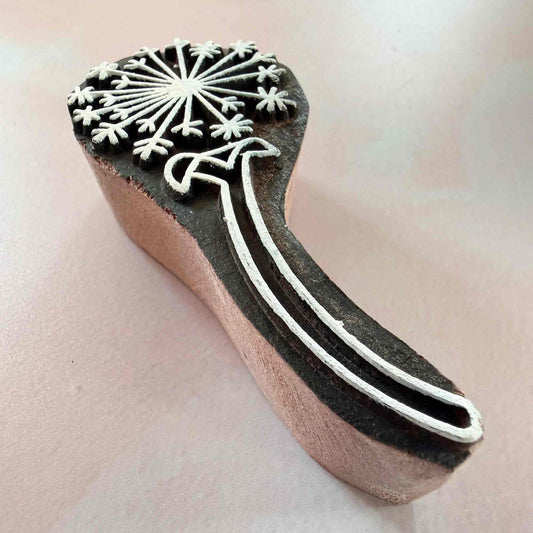 Wooden stamp with snowflake design on a light pink background