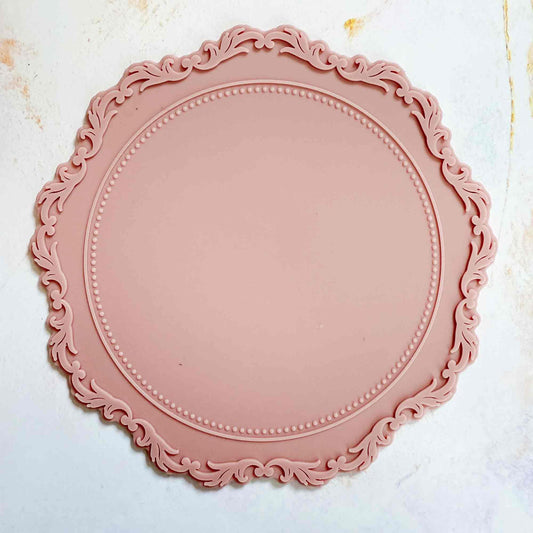 Pink decorative plate with intricate border on a light background