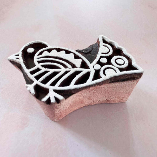 Wooden stamp with bird design on a light pink background