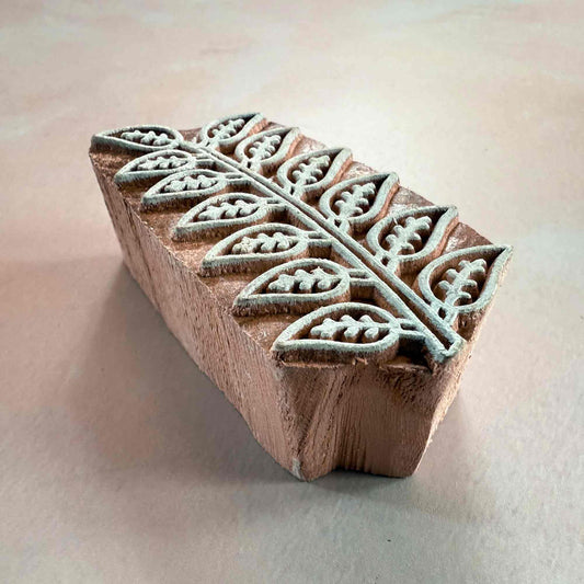 Wooden stamp block with leaf pattern on a light background
