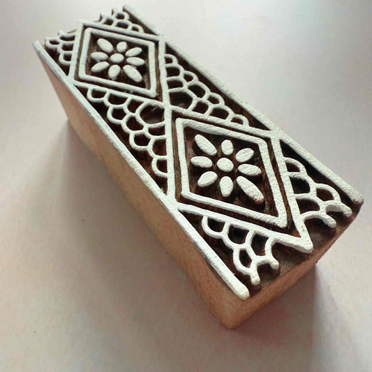 Wooden stamp block with intricate white patterns on a light background