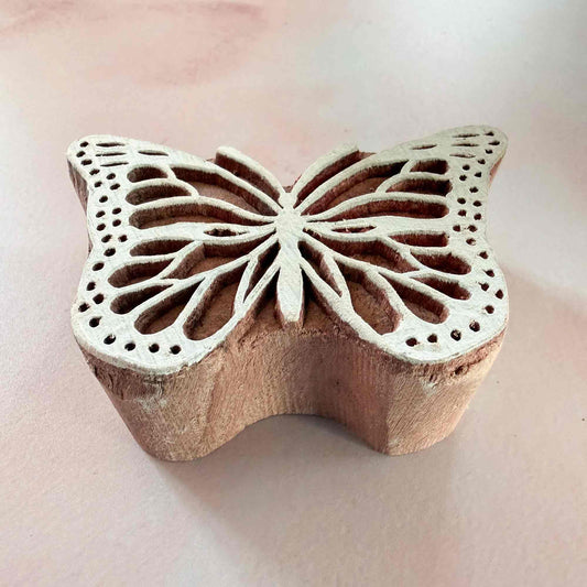 Wooden butterfly stamp on a light pink background