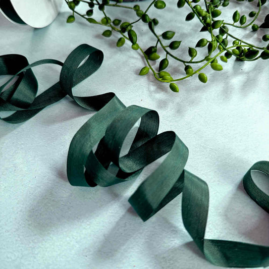 Green ribbons and leaves on a white fabric background