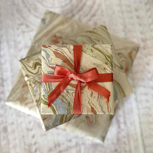 Handmade Lokta paper gift wrap with hand-marbled pattern, wrapped gift boxes tied with orange ribbon – sustainable eco-friendly wrapping paper