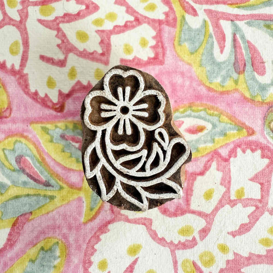 Decorative wooden stamp with floral design on a colorful fabric background