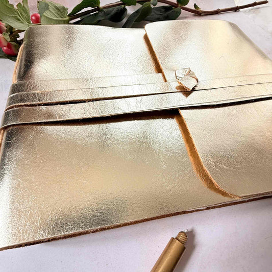 Gold leather clutch with decorative button on a light background