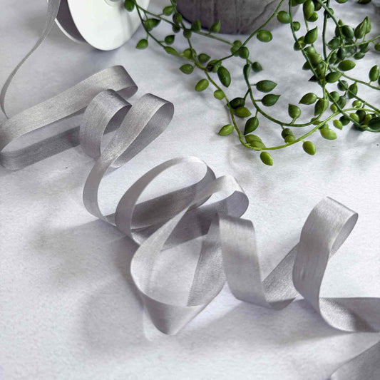 Silver ribbons on a textured white surface with green leaves.