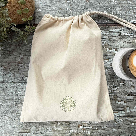 Beige drawstring bag with a logo on a wooden surface