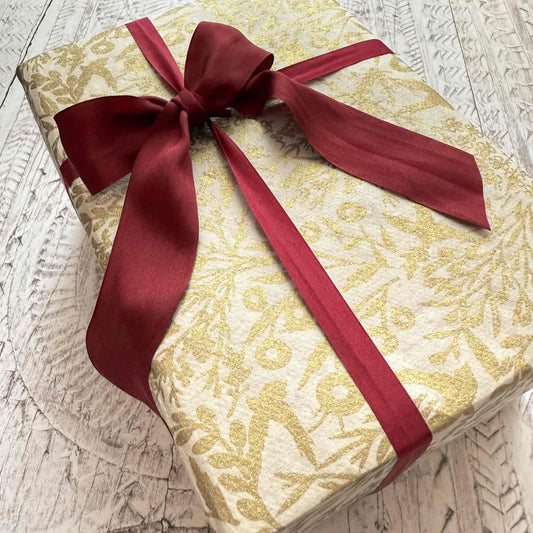 Gift box with gold pattern and red ribbon on a textured surface