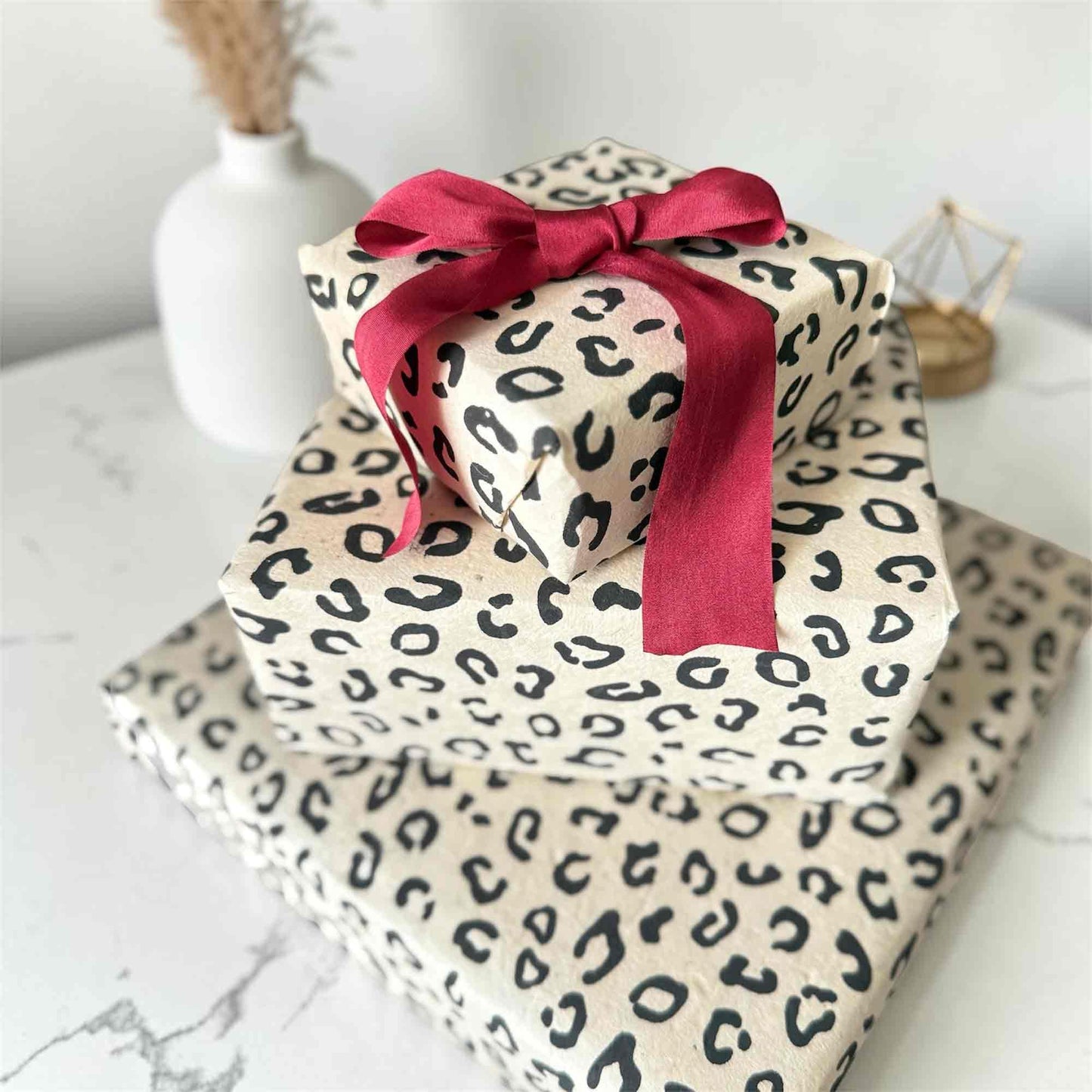 Three gift boxes wrapped in hand screen-printed leopard print Lokta paper – sustainable artisanal gift wrap