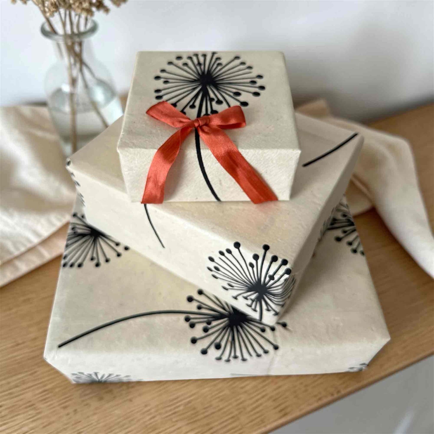 Stacked gift boxes wrapped in eco-friendly Lokta paper, dandelion design, artisan wrapping paper