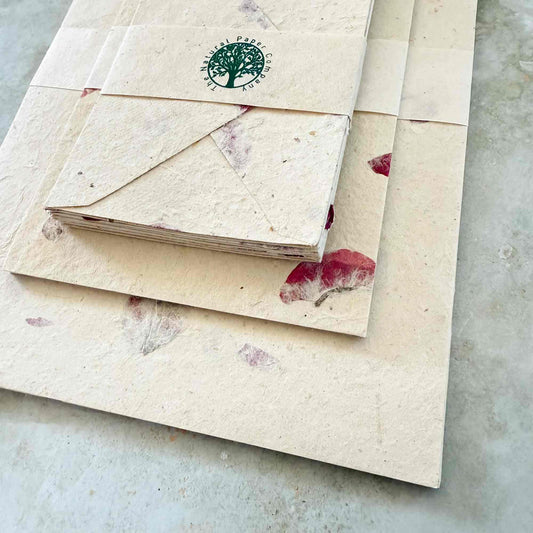 Stack of eco-friendly notebooks and envelopes with a visible brand logo on a textured surface.