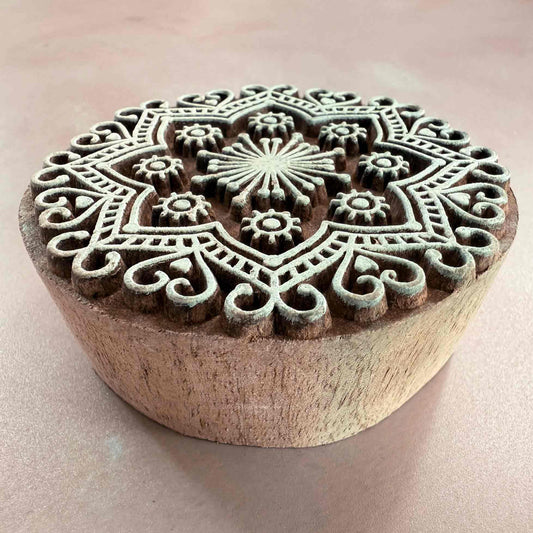 Wooden stamp with intricate mandala design on a light pink background