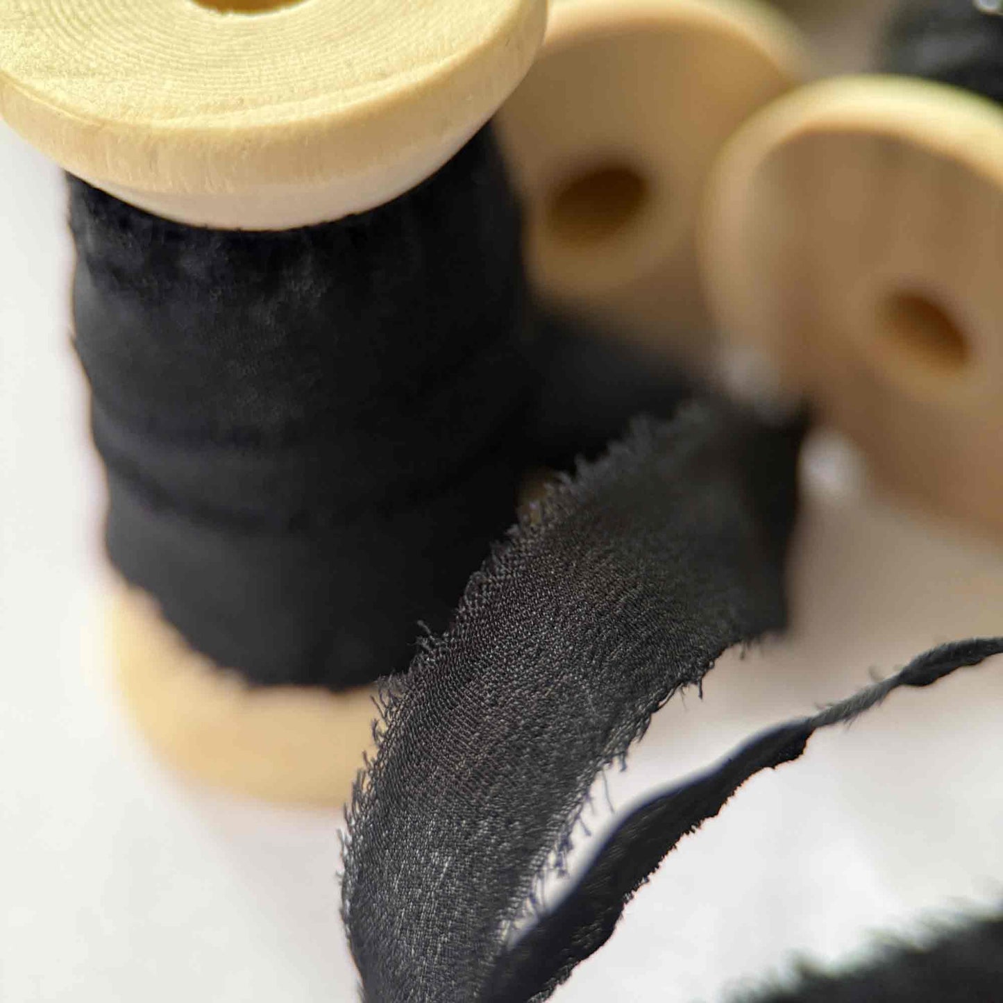 Close-up of black fabric on a wooden spool with a white background