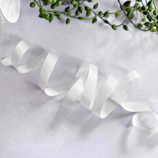 White ribbon on a white background with green leaves.