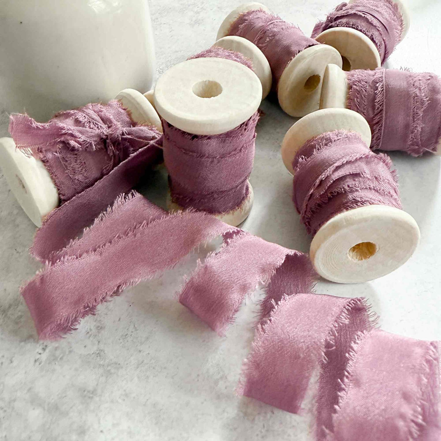 1cm wide silk ribbon in mauve. Raw edge silk ribbon on a wooden reel