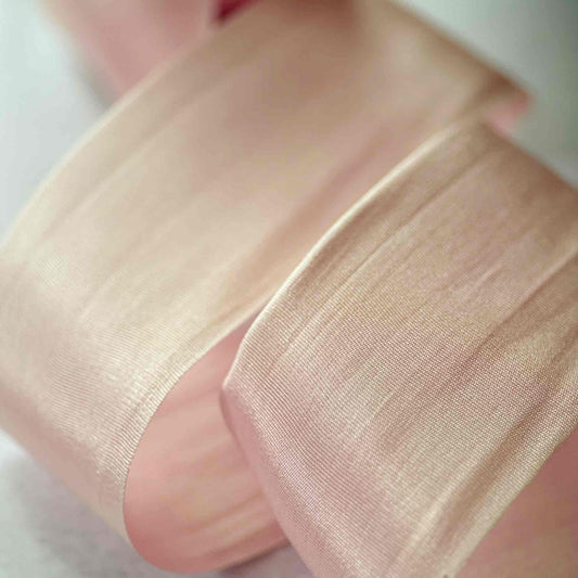 Close-up of a hand wearing sheer beige fabric over a white background