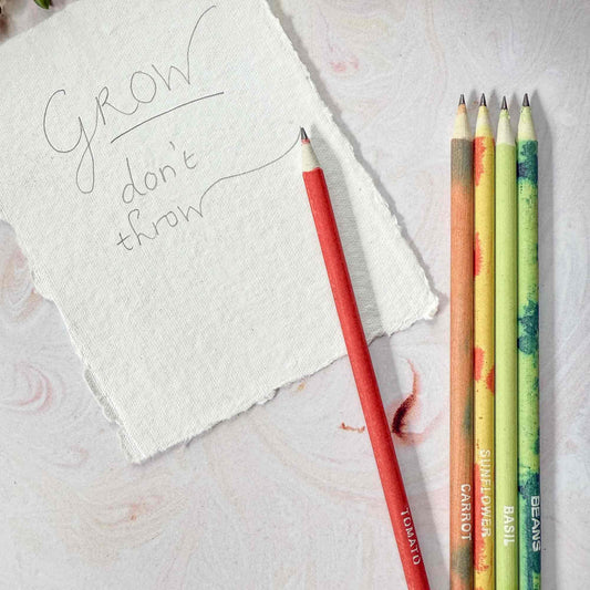 Set of colorful pencils with plant-themed designs on a light surface next to a piece of paper with 'Grow don't throw' text.