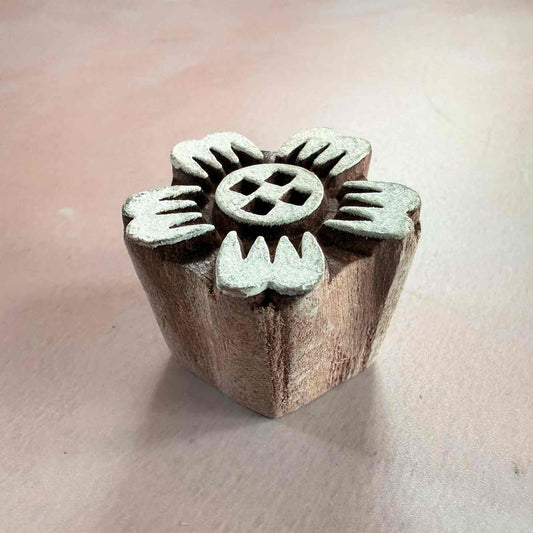 Wooden stamp with metal dies on a light pink background