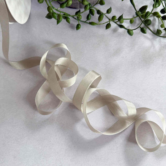 Ivory ribbon on a light gray background with green leaves.