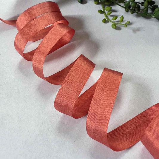 Coral ribbon on a white background with green leaves