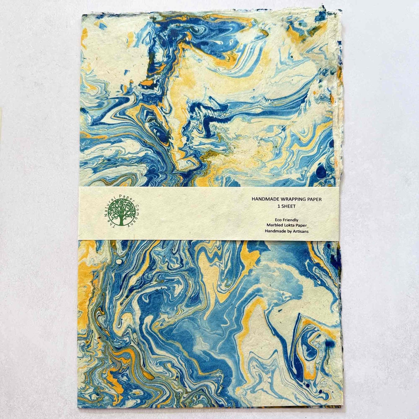 Full sheet of hand-marbled Lokta wrapping paper showing textured natural edges and swirling blue and gold pattern