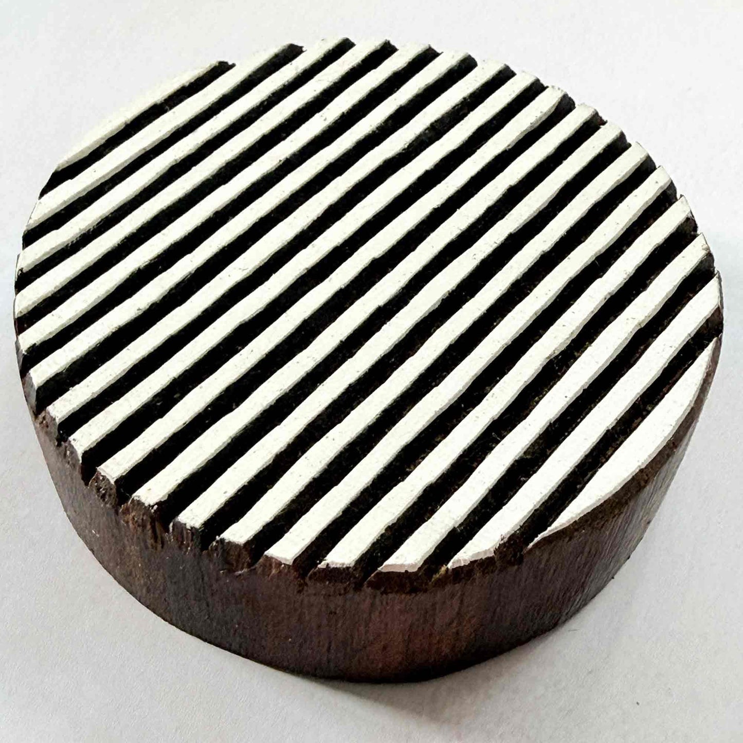 Shield wooden stamp — striped circle design viewed from angle, showing carved depth and fine parallel groove texture, substantial handcrafted Indian hardwood printing block