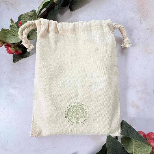 Beige drawstring bag with a green logo on a light background