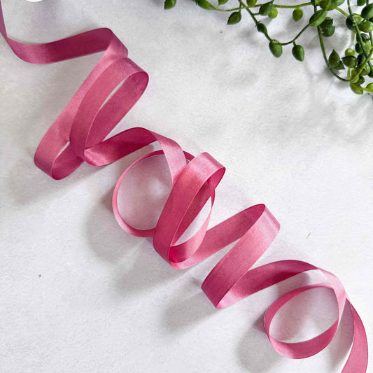 Pink ribbon on a white background with green leaves