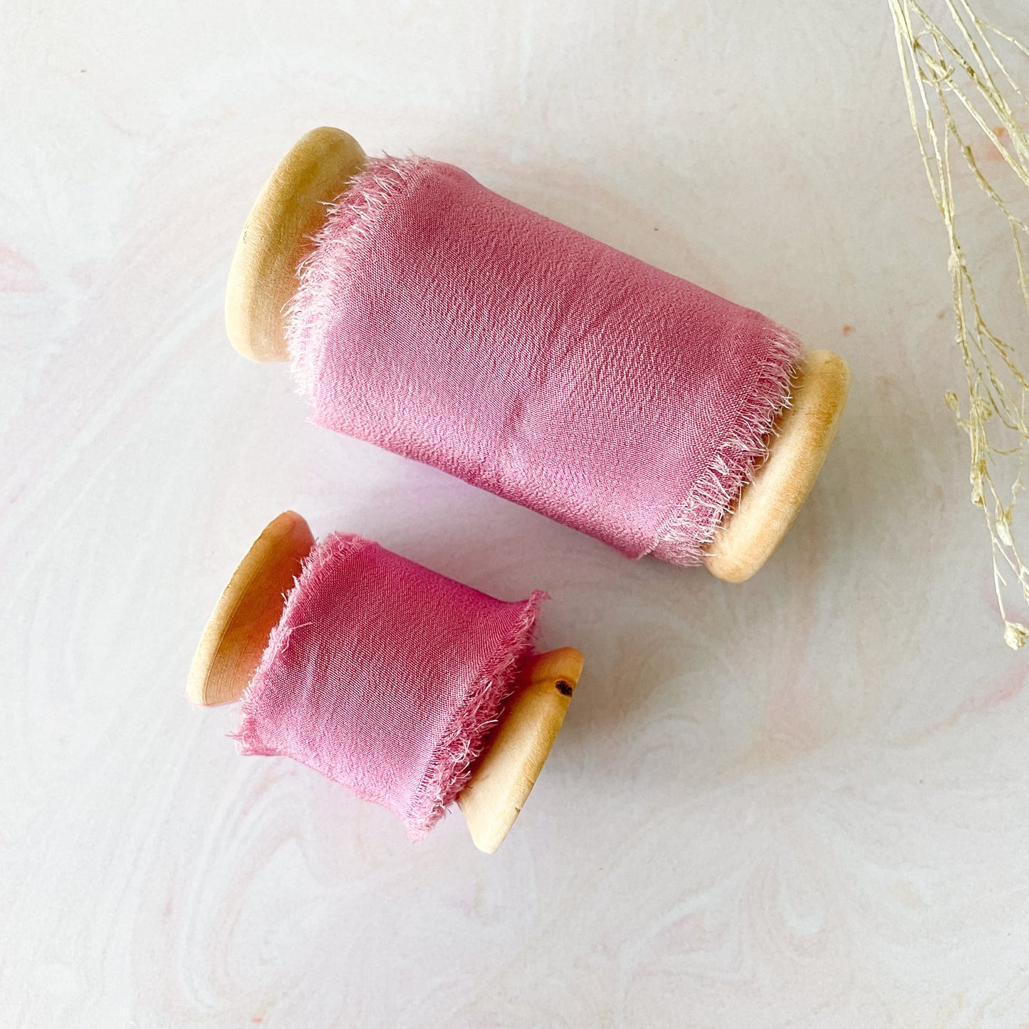 Luxury silk ribbon in bright pink colour. Raspberry pink habotai silk ribbon on a wooden reel. Beautiful ribbon for decorating wedding stationery, crafts and floristry. By The Natural Paper Company.