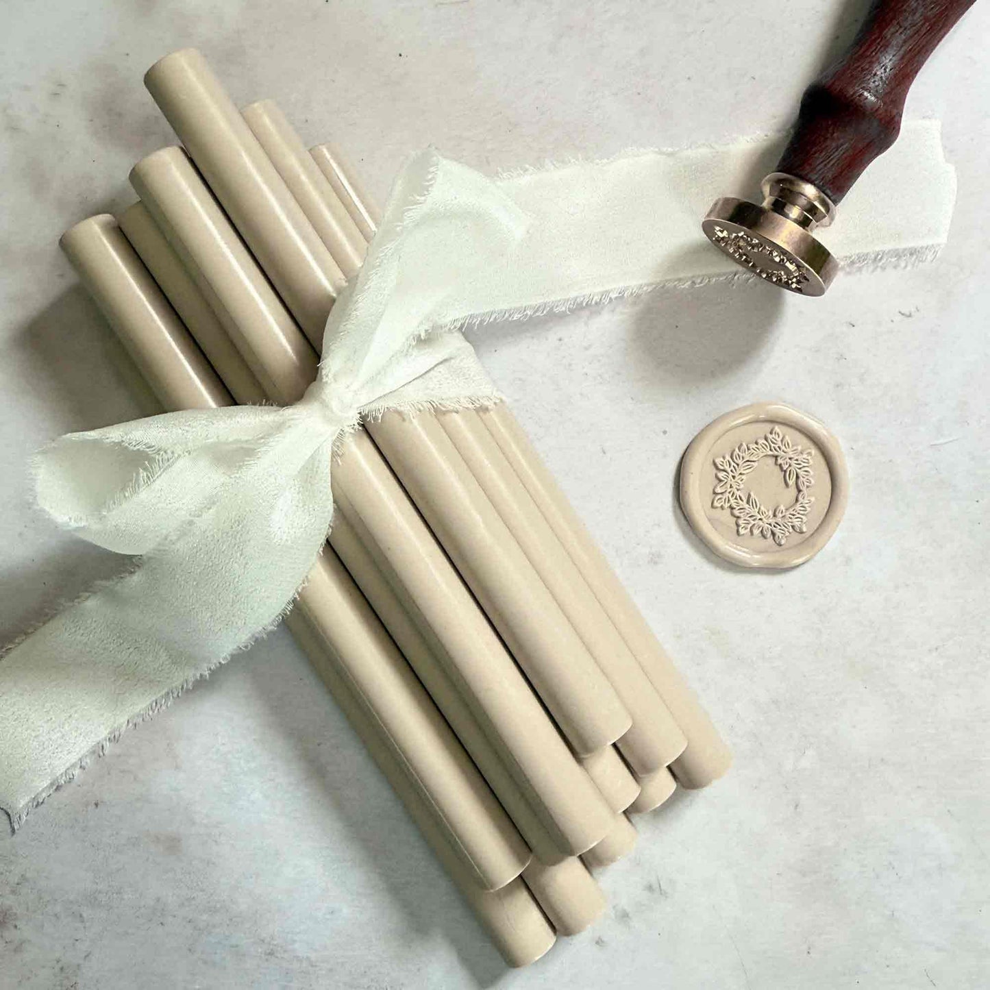 Set of beige sealing wax sticks with a decorative wax seal on a light background