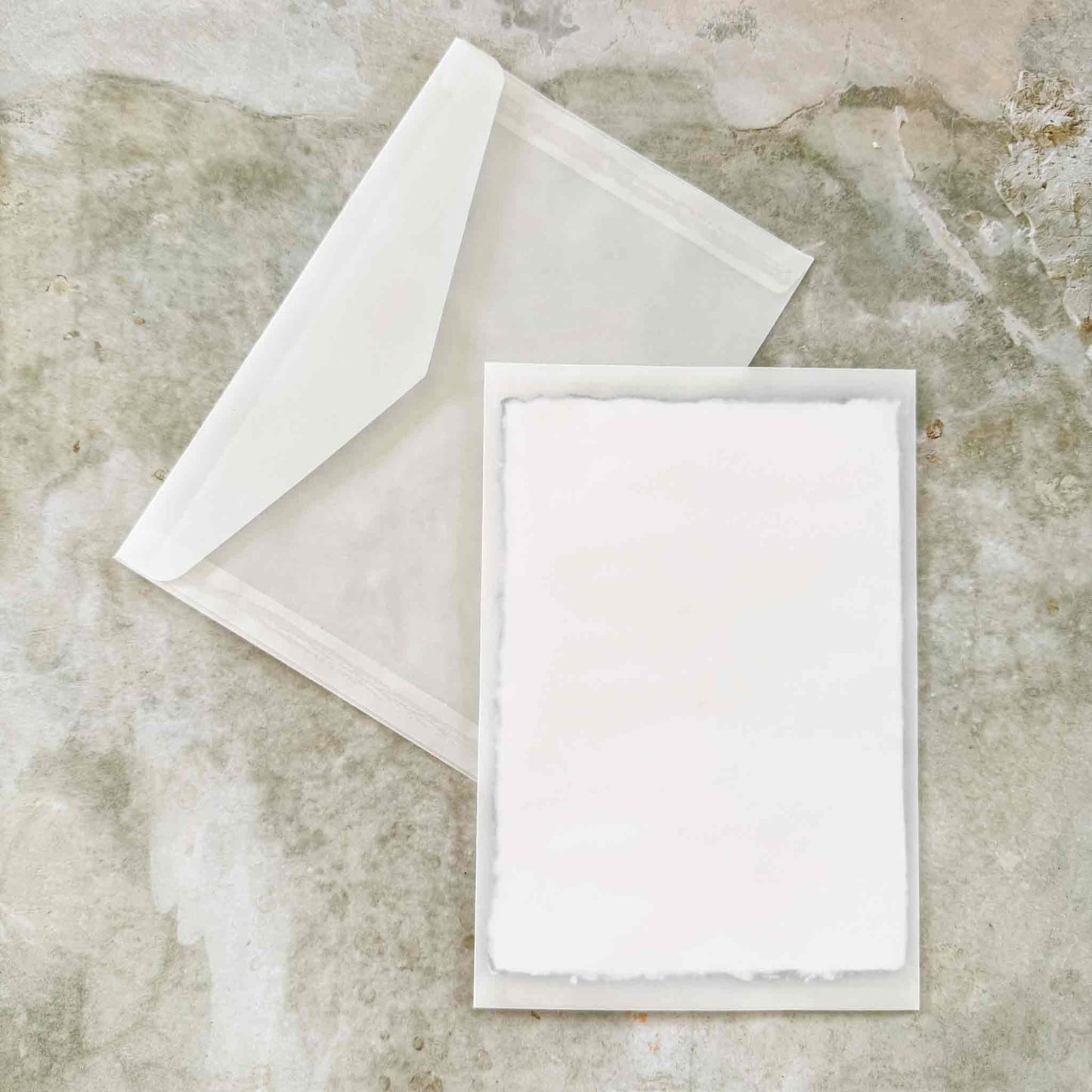 White card and envelope on a textured stone surface