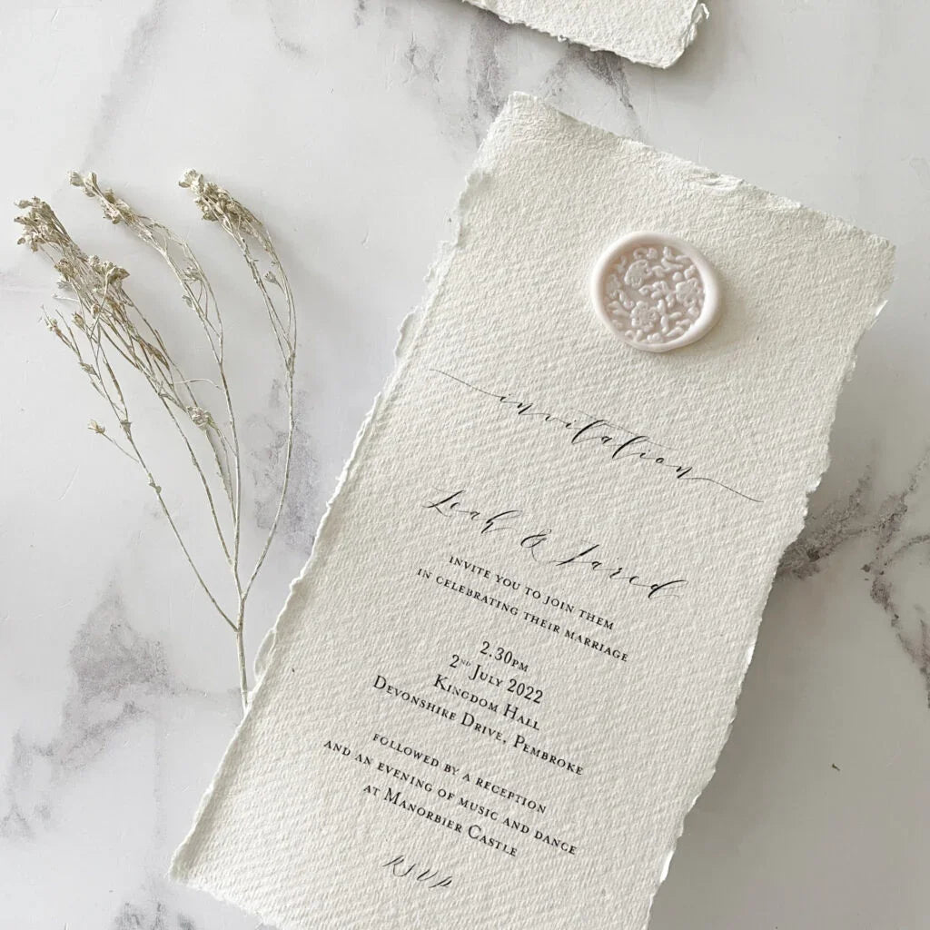 Handmade wedding invitation made using eco friendly materials. Recycled cotton rag paper, eco friendly sealing wax and a wax seal in blush pink and ivory. By The Natural Paper Company