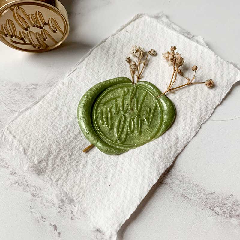 With love wax seal made using a calligraphy style sealing wax stamp and eco friendly wax in olive green. By The Natural Paper Company