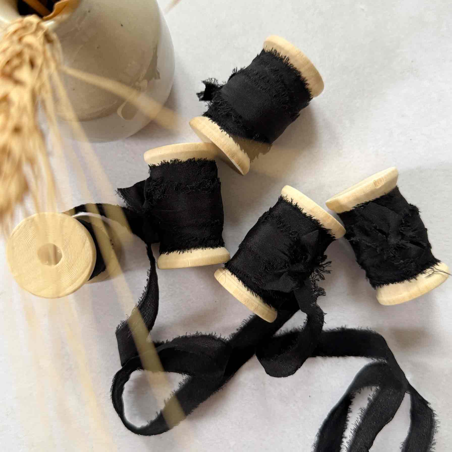 Black ribbon on wooden spools with a white background