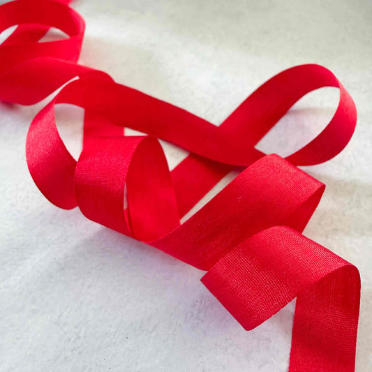 Narrow 13mm Berry Red silk ribbon arranged in flowing loops, ideal for invitations, gifts and wedding styling.