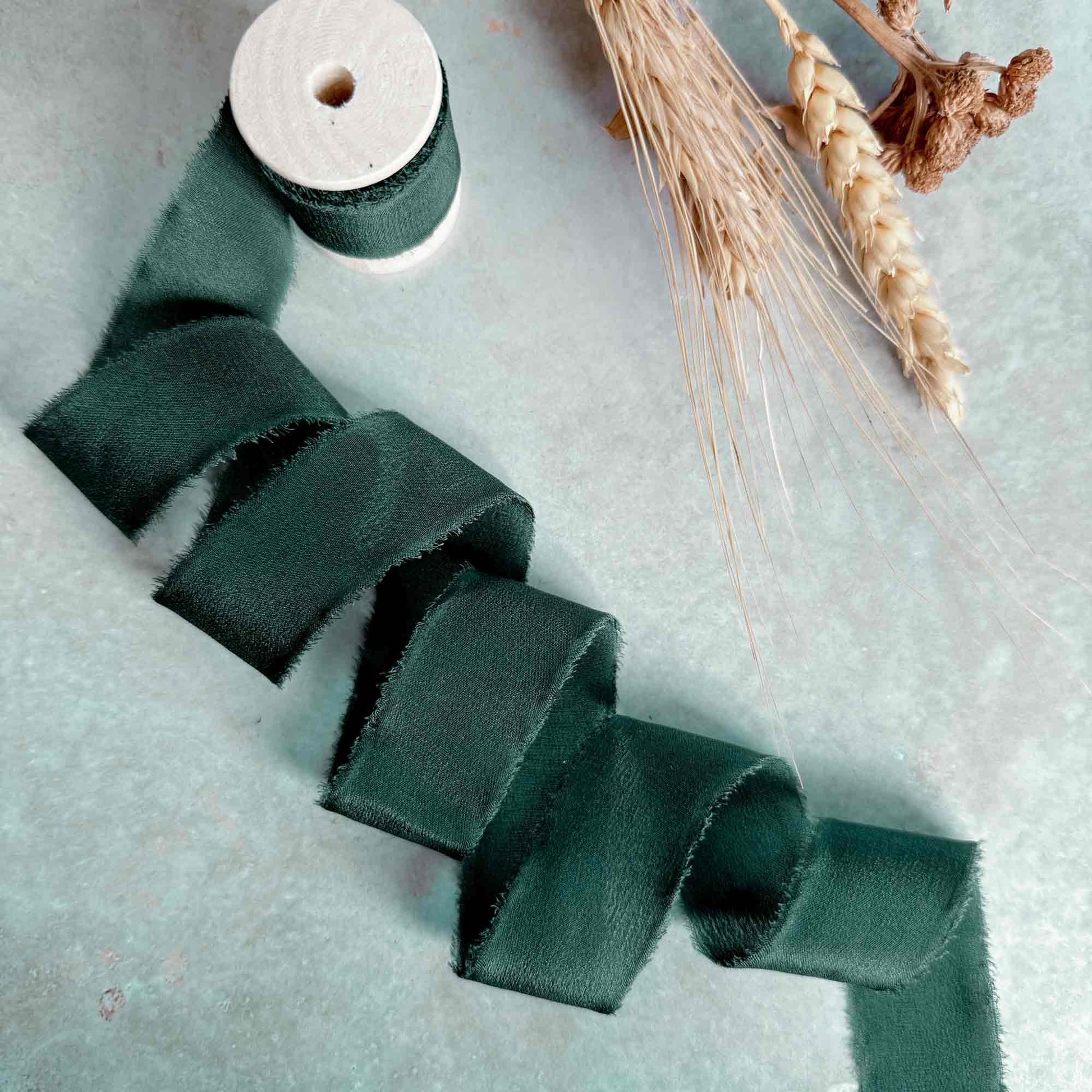 25mm forest green silk ribbon on a wooden reel