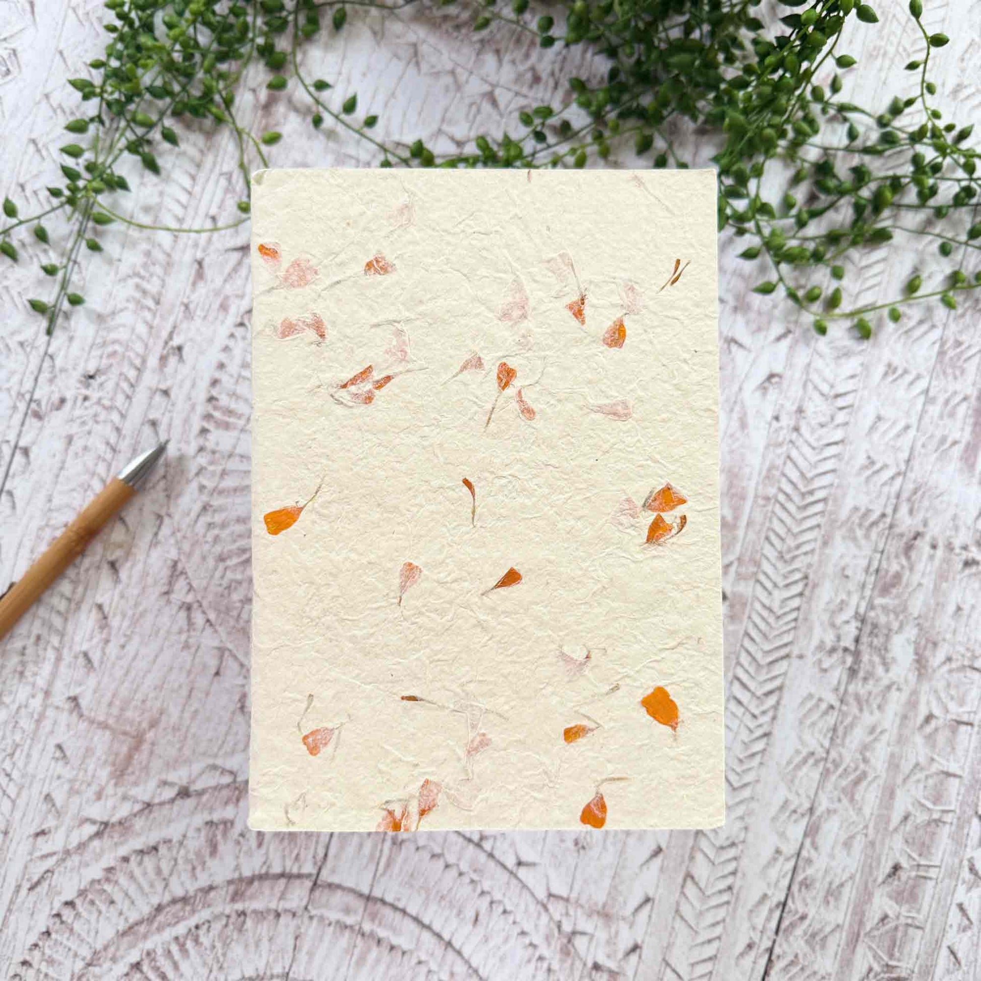 A5 botanical Lokta notebook, natural cream paper embedded with warm orange Marigold petals, hand‑stitched and sustainably made in Nepal