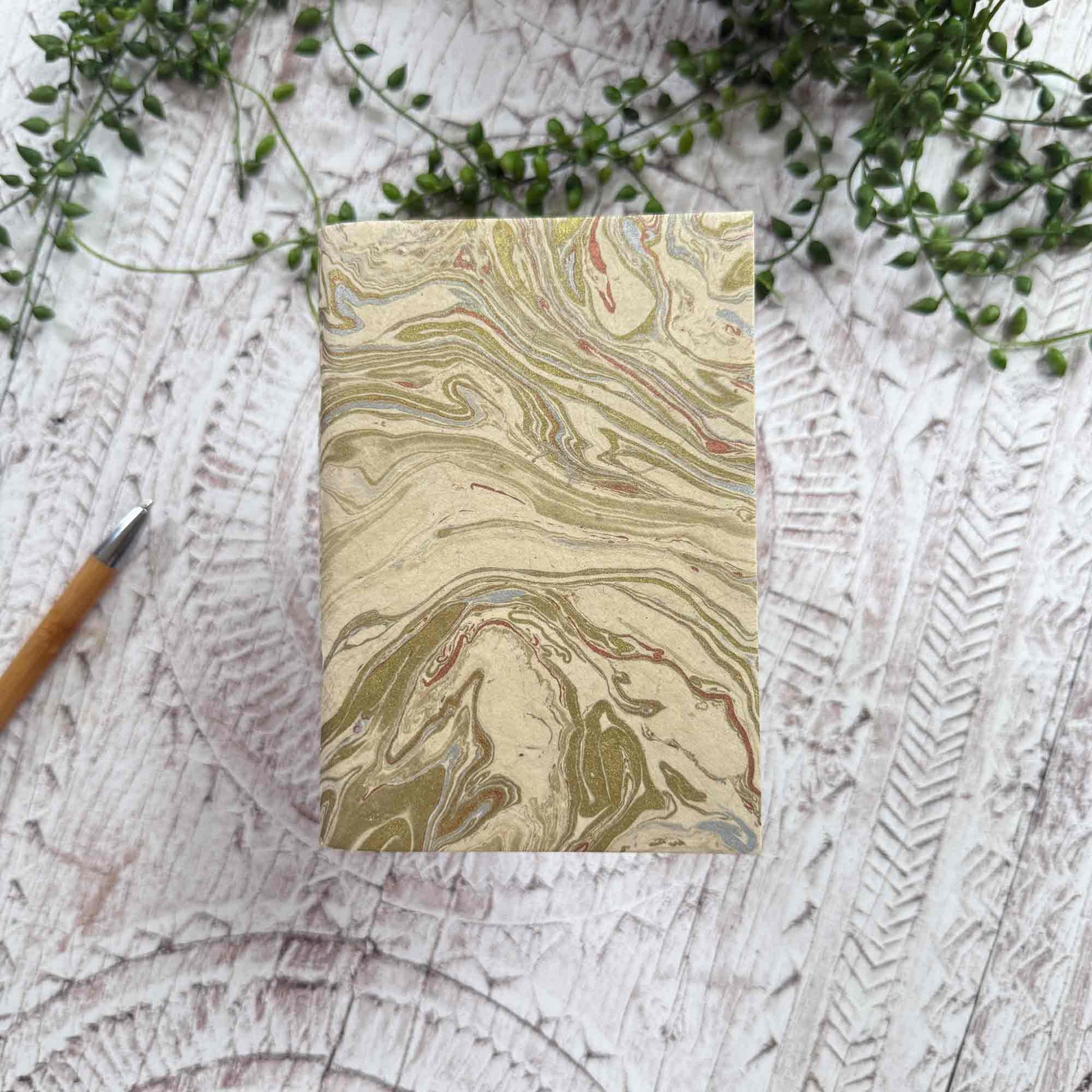 Compact A6 Midas Marble pocket notebook, hand‑marbled gold and copper design, made from sustainable Lokta paper with hand‑stitched binding