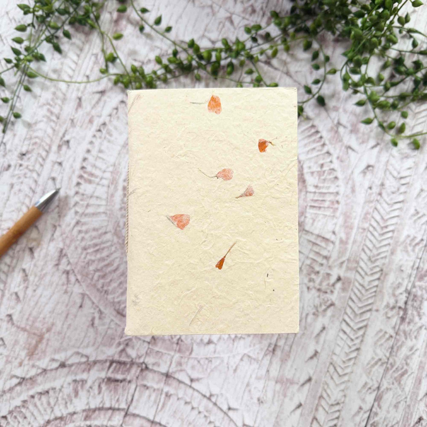 Compact A6 eco‑friendly Lokta notebook, embedded with delicate orange Marigold petals, hand‑stitched binding, tree‑free and ethically produced