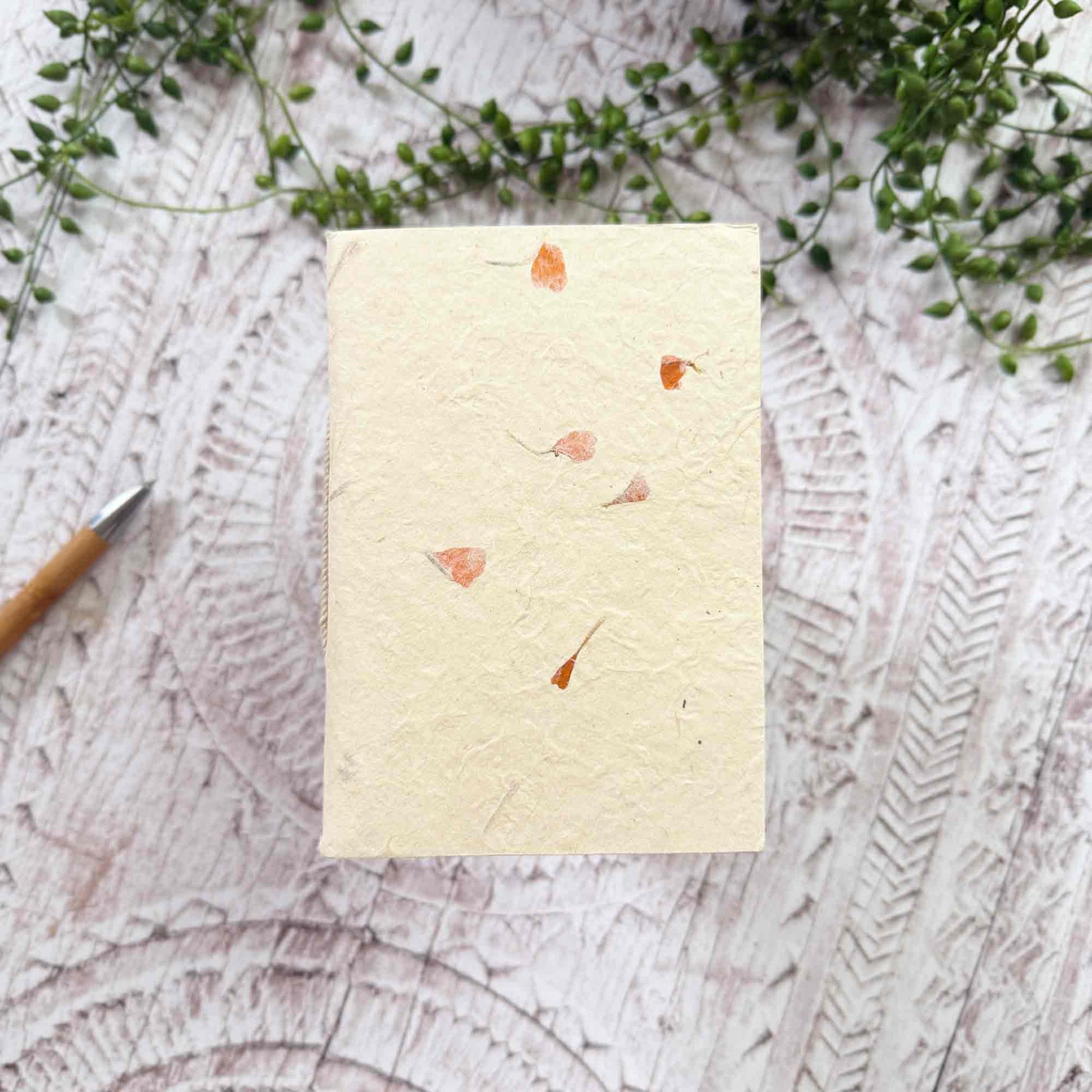 Compact A6 eco‑friendly Lokta notebook, embedded with delicate orange Marigold petals, hand‑stitched binding, tree‑free and ethically produced