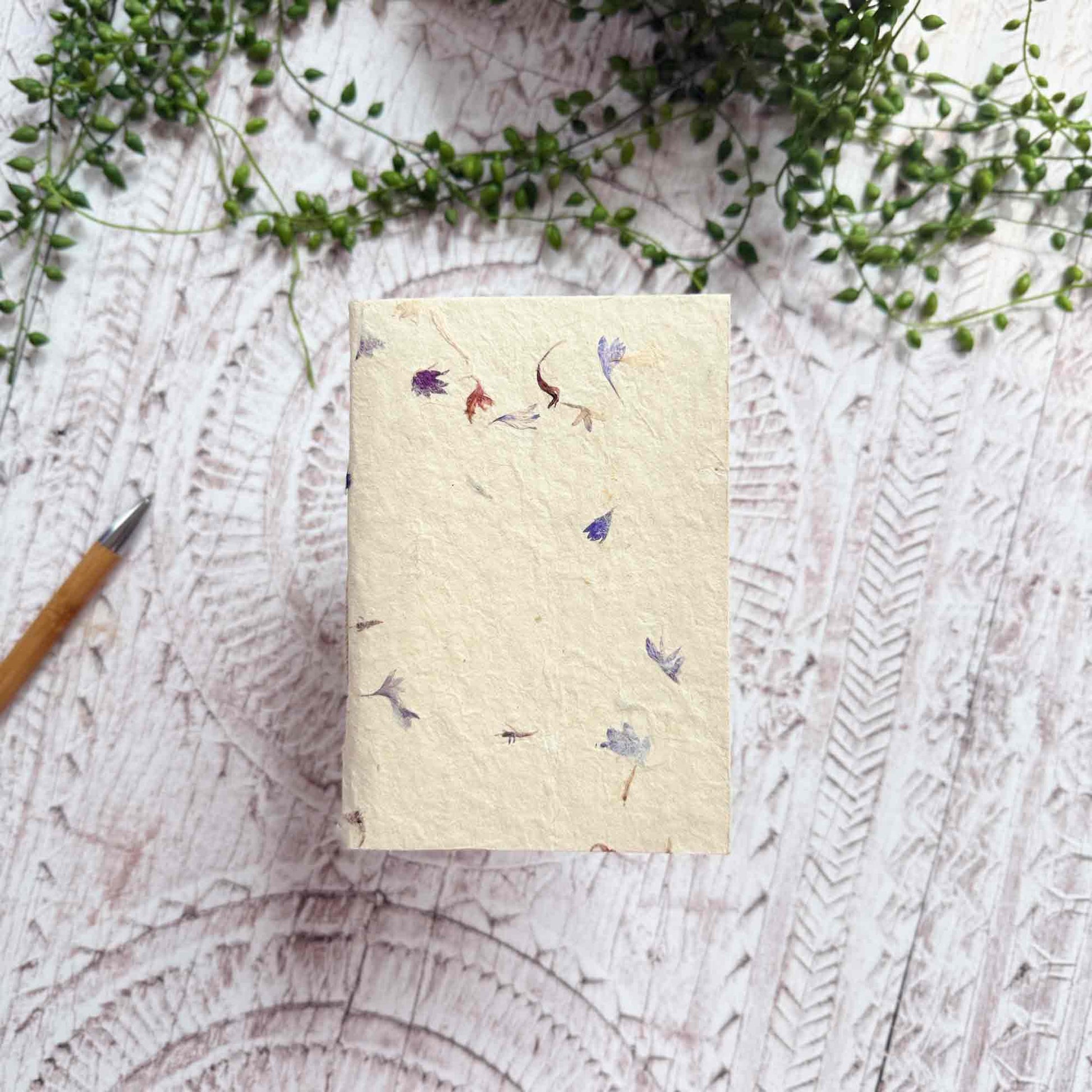 A6 botanical Lokta notebook, natural cream paper decorated with delicate blue and purple Cornflower petals, hand‑stitched and sustainably made in Nepal